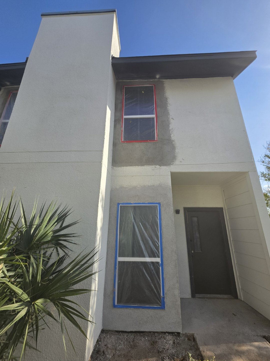 Residential stucco repair — Work in progress · protected windows